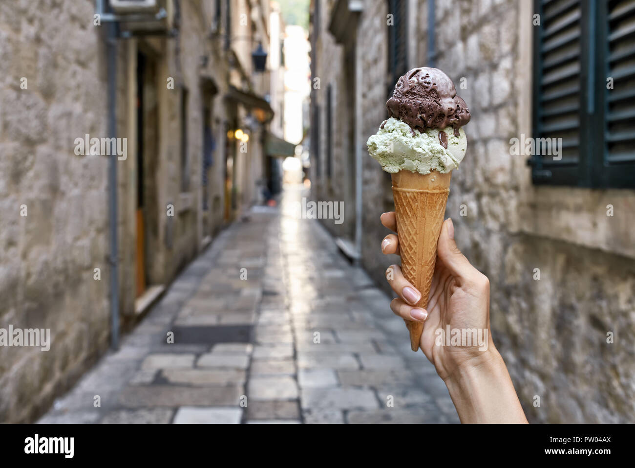 Woman's Hand hält das Eis in der Waffel Kegel auf dem Hintergrund der sonnigen alten Straße in Dubrovnik in Kroatien. Horizontale Foto. Stockfoto