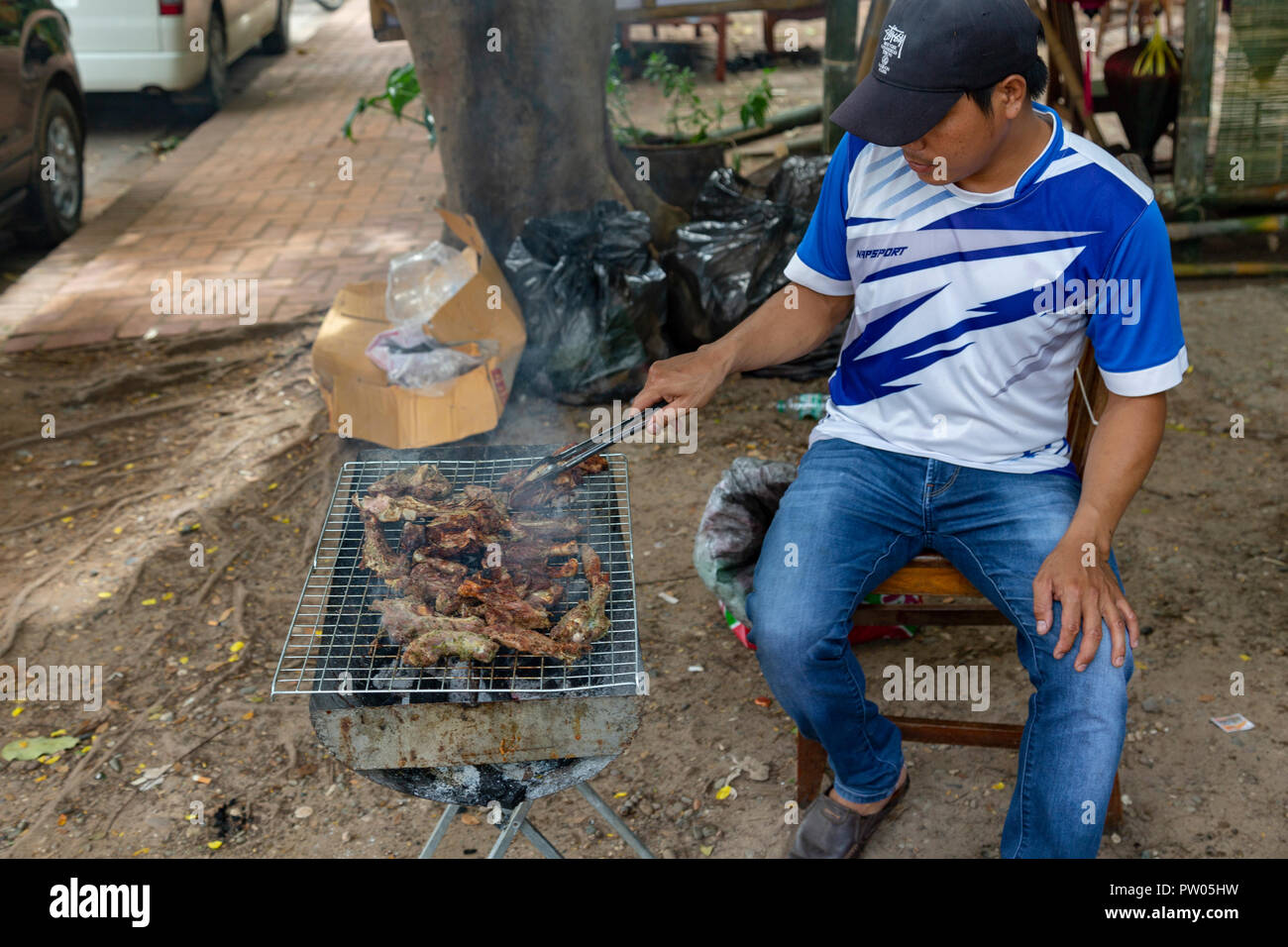 LUANG PRABANG, LAOS - OKTOBER 4: unbekannter Mann gegrilltes Fleisch auf der Seite der Straße am 4. Oktober in Luang Prabang, Laos 2017. Stockfoto