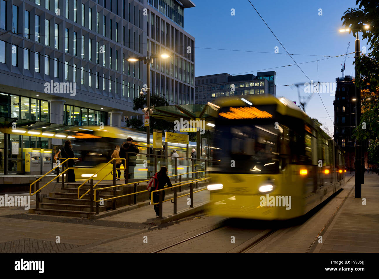 Zwei Metrolink Tram verlassen St. Peter's Square Stop in der Nacht im Stadtzentrum von Manchester, UK. Stockfoto