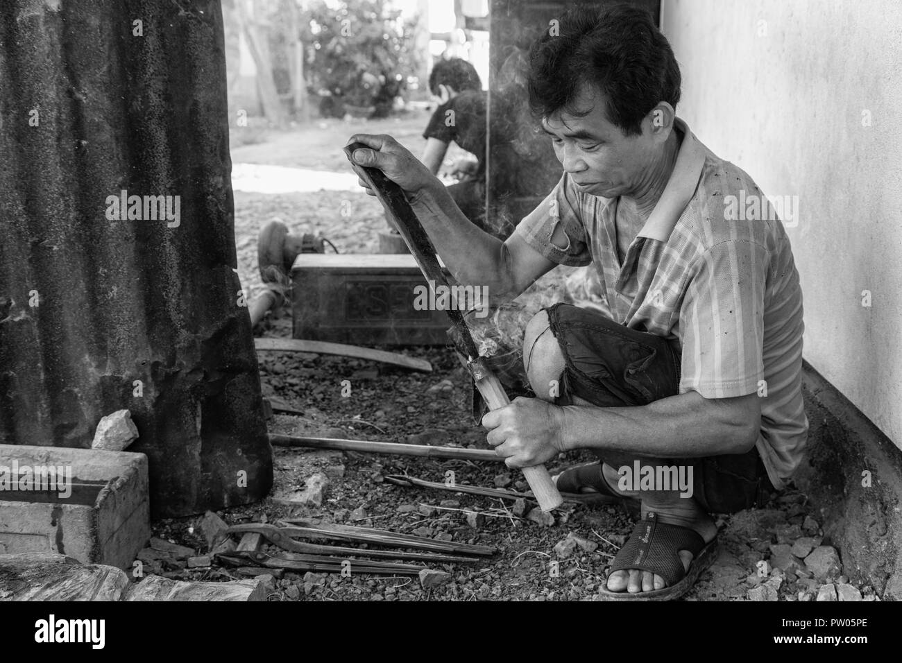 LUANG PRABANG, LAOS - OKTOBER 8: Ein unbekannter Mann brennt ein Messer in einem in einem lokalen Dorf in Luang Prabang, Laos am 8. Oktober 2017 zu schmieden. Stockfoto