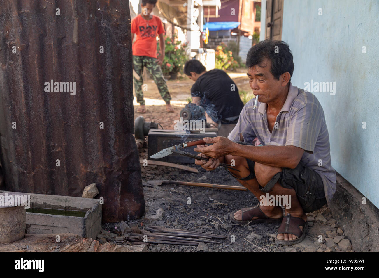 LUANG PRABANG, LAOS - OKTOBER 8: Ein unbekannter Mann sieht einen rauchen Messer in einem lokalen Dorf in Luang Prabang, Laos am 8. Oktober 2017 zu schmieden. Stockfoto