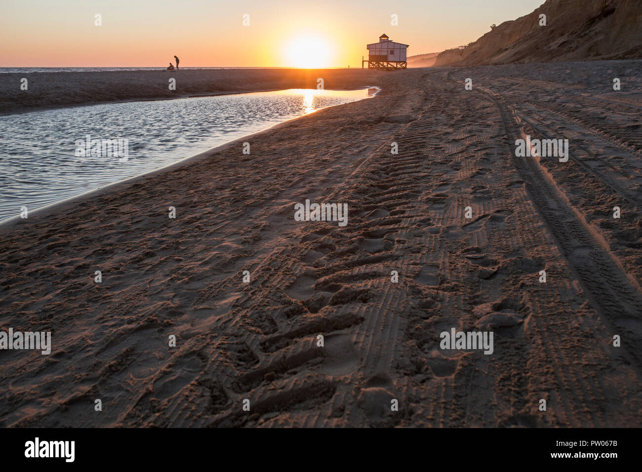 Letzte Schwimmer in der Nähe Chiringuito Strand bei Sonnenuntergang, Costa de la Luz Küste, Matalascañas, Huelva. Sonnenuntergang Stockfoto