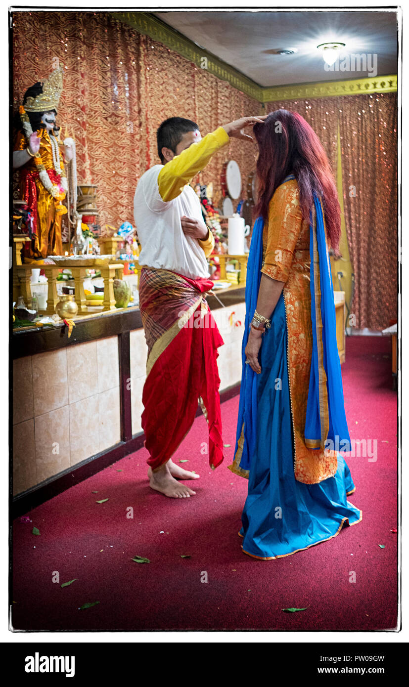 Eine Frau in einem schönen Sari erhält einen persönlichen Segen an einem hinduistischen Mandir (Tempel) in Richmond Hill, Queens, New York. Stockfoto