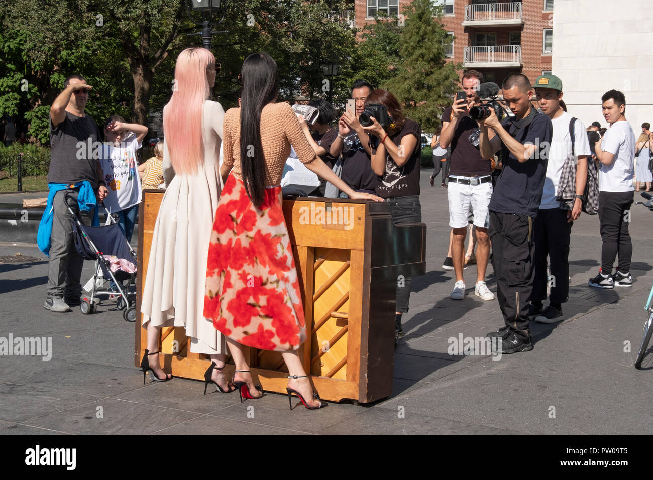 Zwei schöne Schlanke japanische Modelle, ihre Fotografen, Entourage & Zuschauer in Washington Square Park in Greenwich Village, New York City. Stockfoto