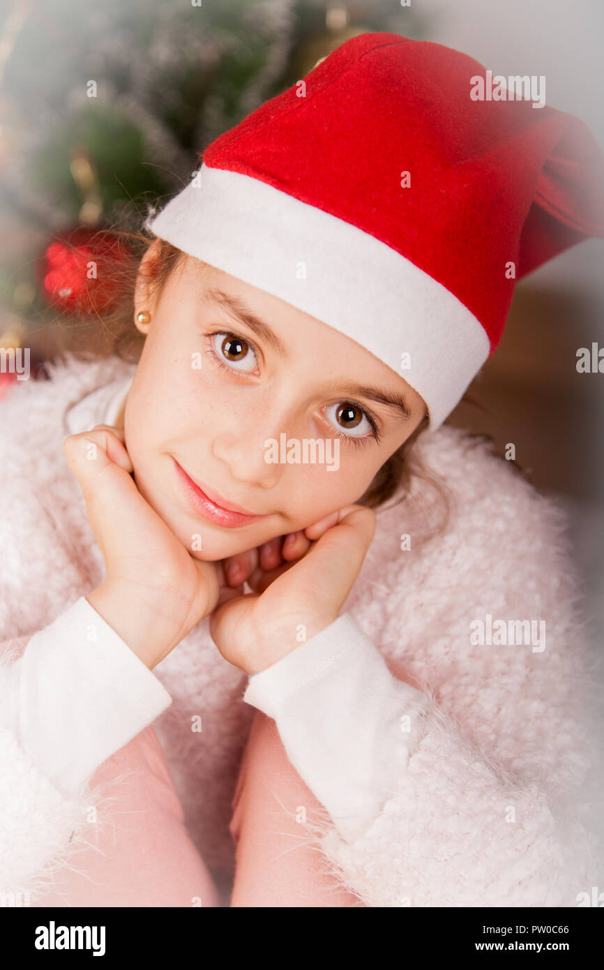 Mädchen mit weißer Weste und mit Santa Hut lächelnd im Studio Stockfoto