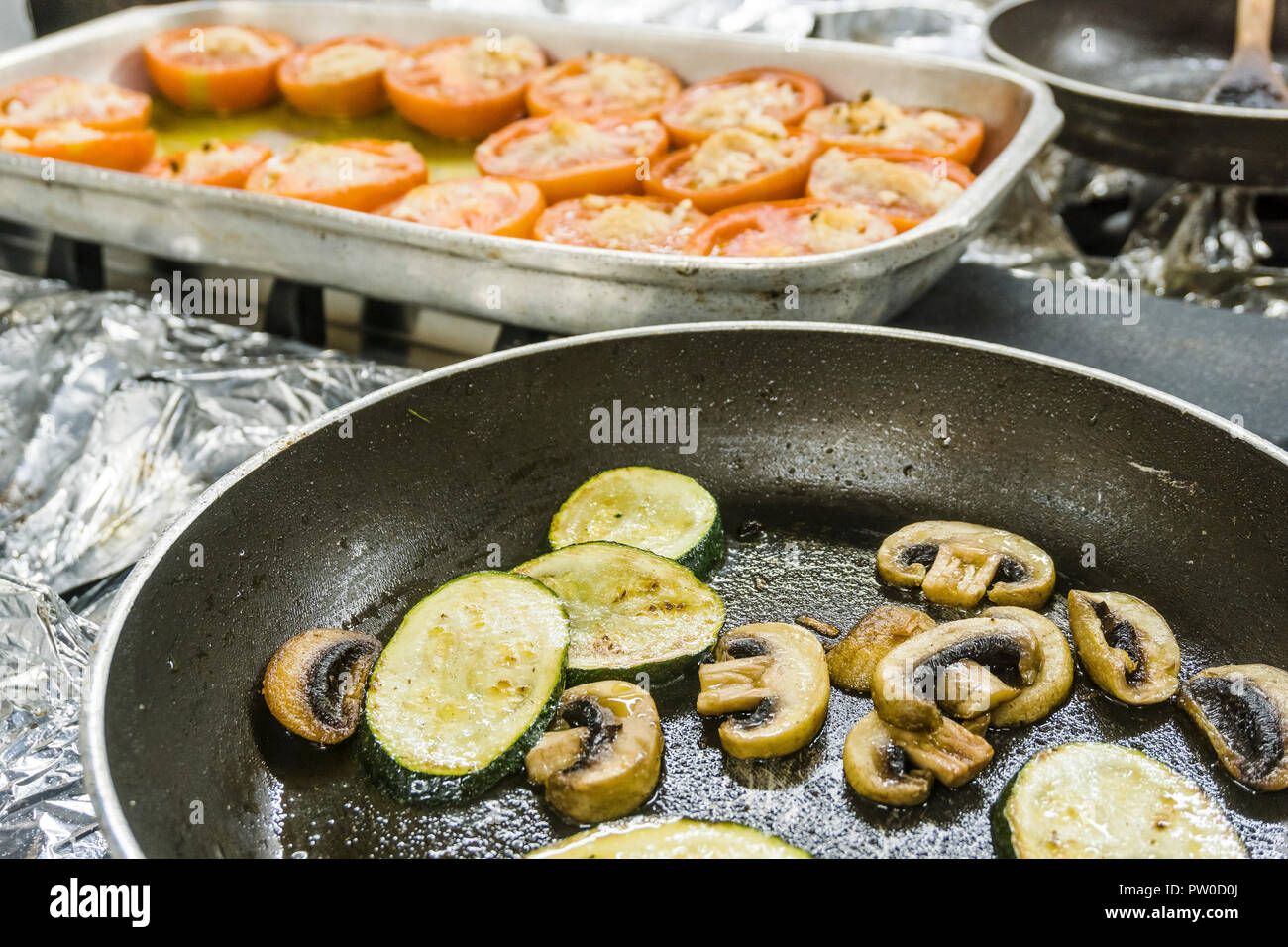 Gebratene Zucchini und Pilze und gebackene Tomaten mit geschmolzenem Käse auf der Oberseite Stockfoto