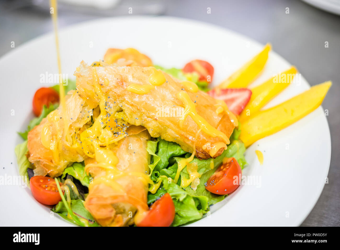 Sea Food Kroketten serviert mit Salat, Tomaten und Mango auf weiße Platte Stockfoto