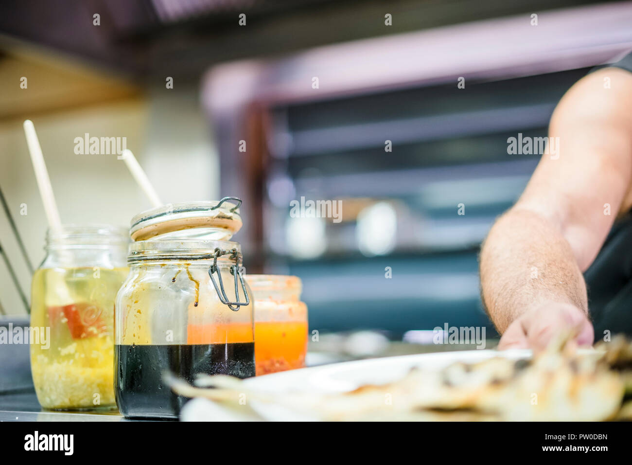 Man Fisch für den Grill mit bunten würzige Saucen im Vordergrund Stockfoto