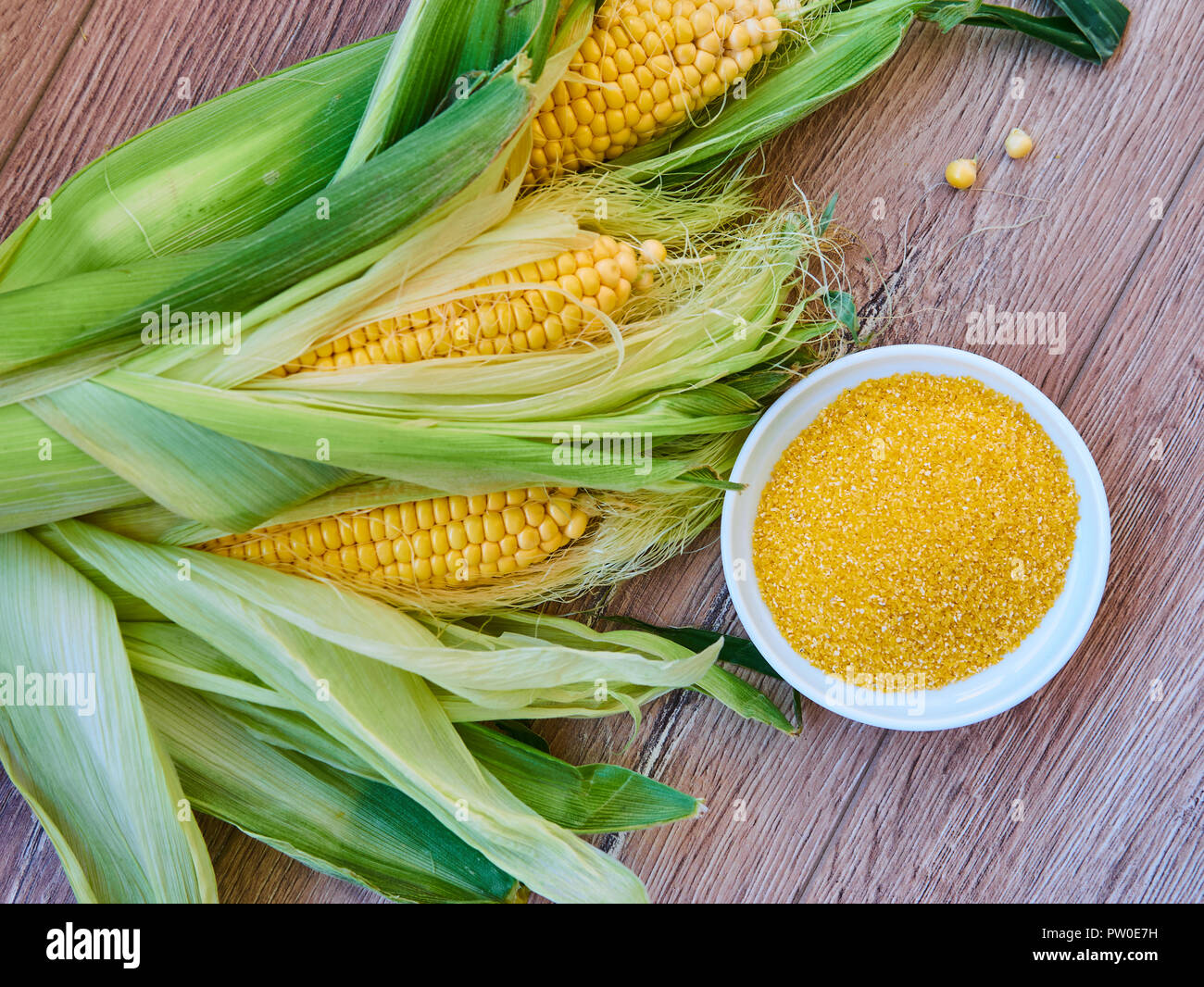 Maiskolben mit einer Schüssel mit Mais Körnungen auf einer hölzernen Hintergrund. ohne Gluten. Glutenfreie Konzept. Stockfoto