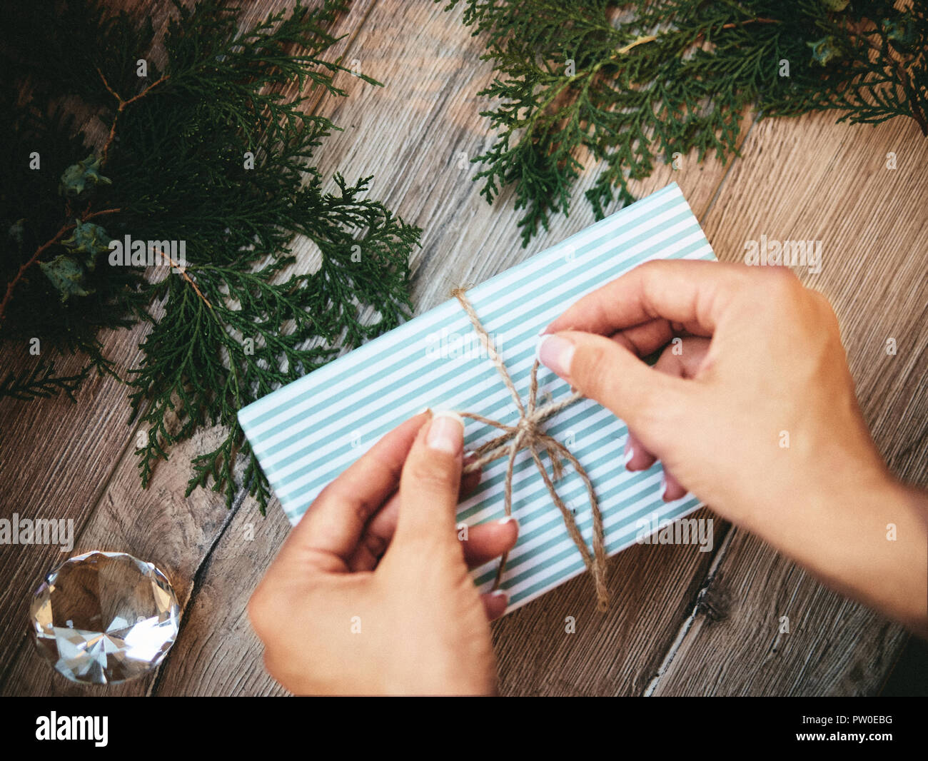 Weihnachten Geschenk in Händen, Tannenzapfen, thuja Filialen auf Holz- Hintergrund. Flach, Ansicht von oben, kopieren Raum Stockfoto