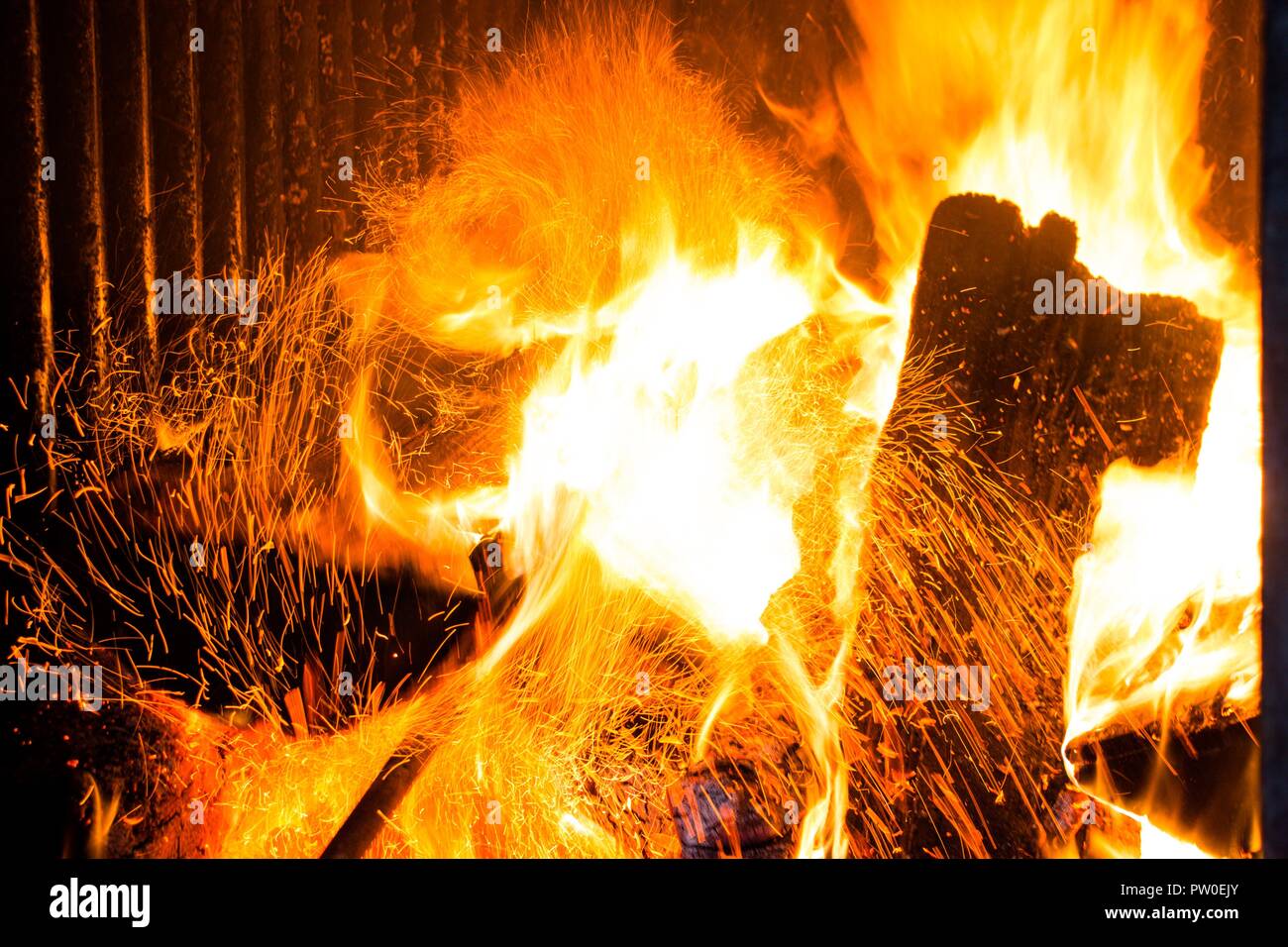 Brennholz in den Herd für die Heizung. Funken aus dem Feuer aufsteigen. Die Temperatur des Planeten ist sehr hoch. Stockfoto