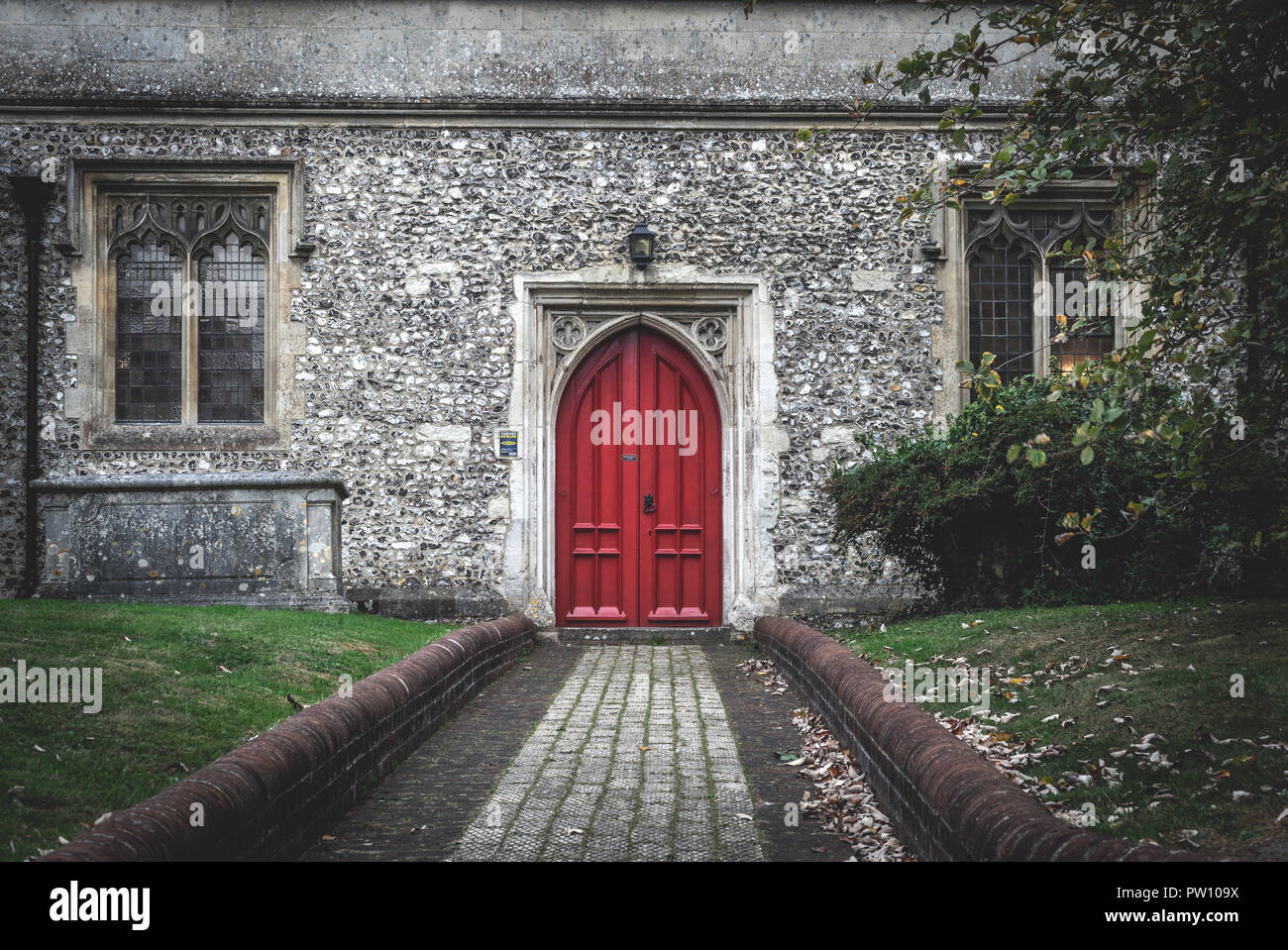 Rote Tür eines alten englischen Kirche Gebäude, stimmungsvolle Atmosphäre, Großbritannien Stockfoto
