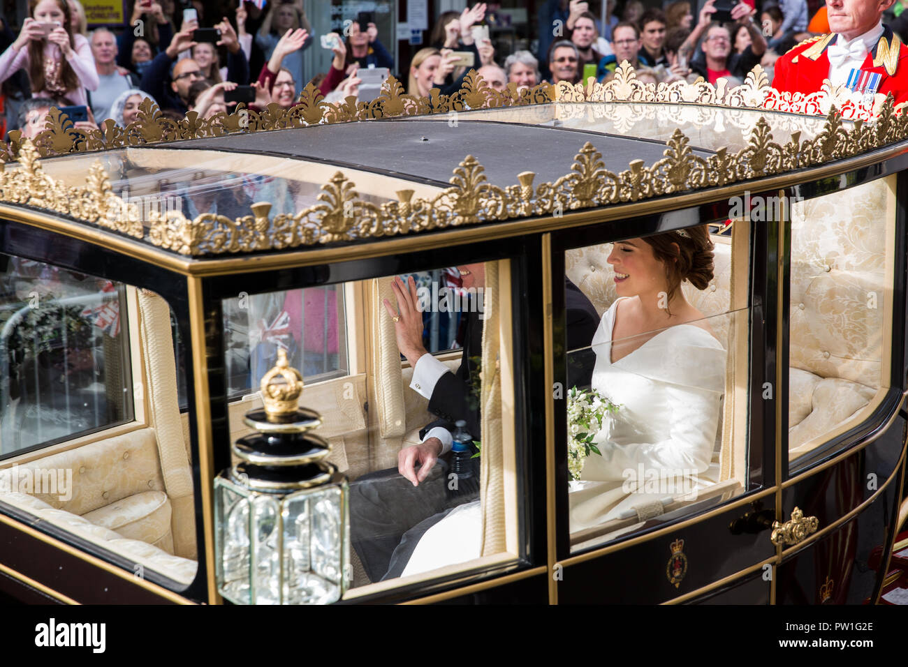 Windsor, Großbritannien. 12. Oktober, 2018. Ihre königliche Hoheit Prinzessin Eugenie, Frau Jack Brooksbank, und ihr Ehemann Jack Brooksbank eine Beförderung Prozession entlang Windsor High Street nach ihrer Hochzeit in St. George's Chapel in Windsor Castle genießen. Die geschlossenen schottischen Zustand Trainer war aufgrund der hohen Winde verwendet. Credit: Mark Kerrison/Alamy leben Nachrichten Stockfoto