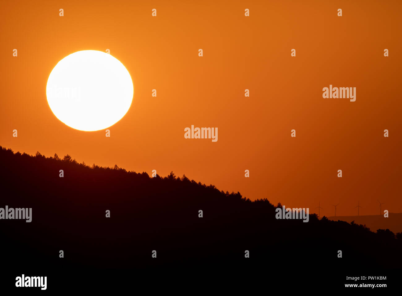 Big Sun Kreis bei Dämmerung über Berge mit Orange Sky Stockfoto