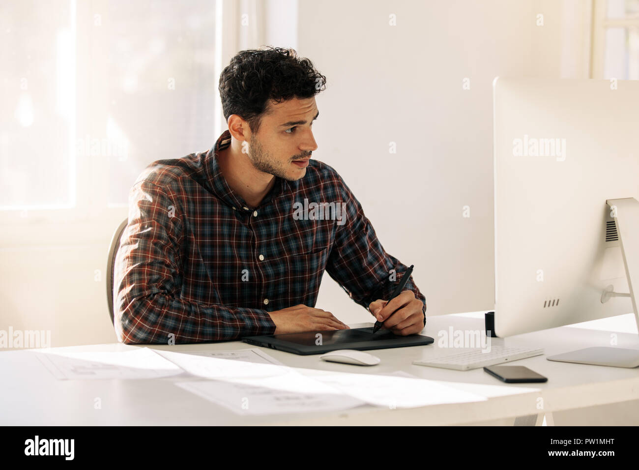 Mann, der an seinem Schreibtisch im Büro Schreiben auf eine digitale Schreibunterlage am Computer sitzen. Unternehmer Notizen über elektronische Schreibblock sitzen Stockfoto