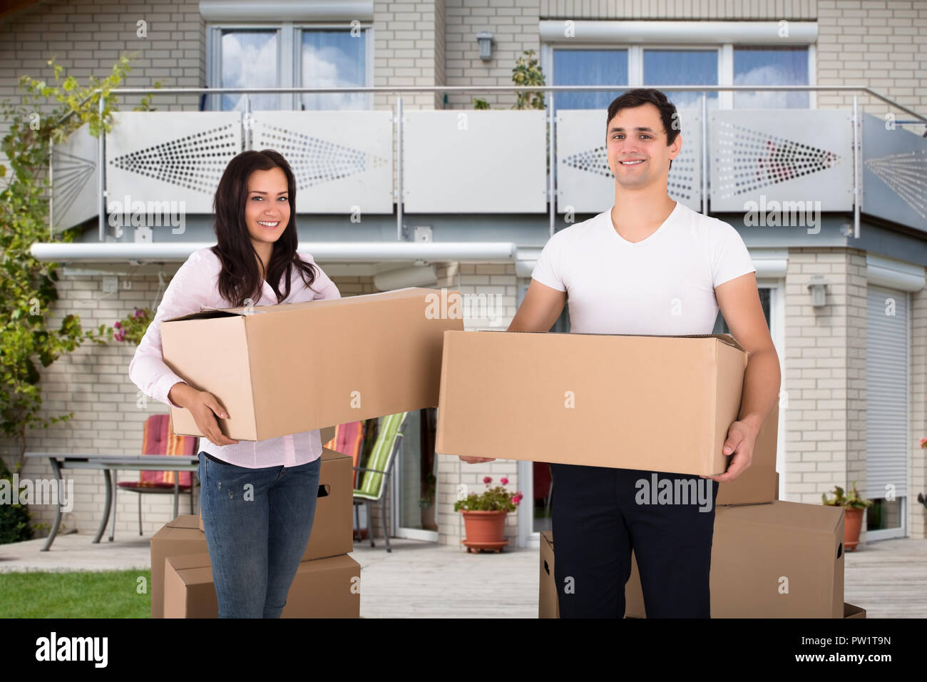 Porträt eines glückliches junges Paar hält Karton Vor Ihrem Haus Stockfoto