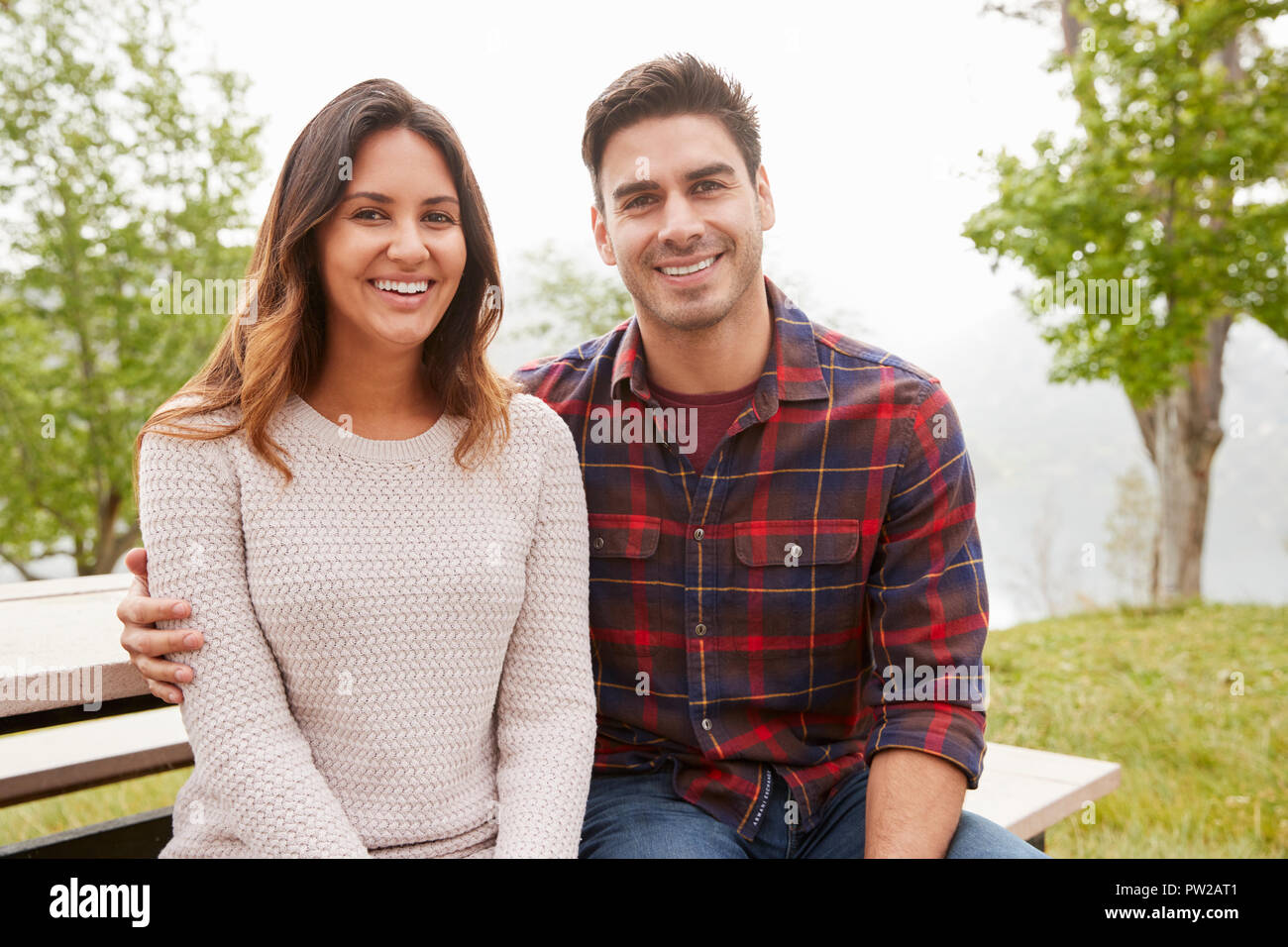 Junge lächelnde Paar sitzen in einem Park Stockfoto