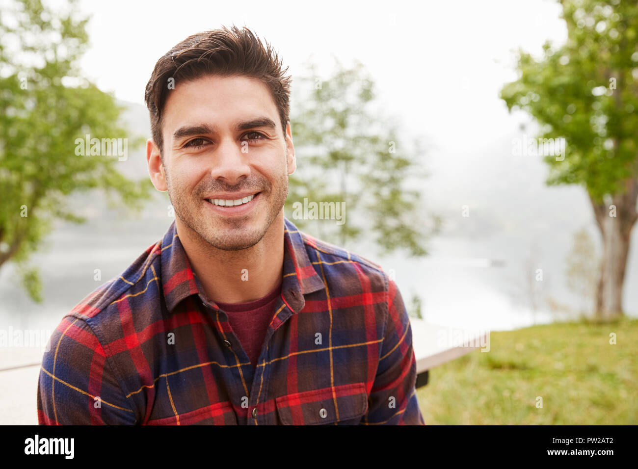 Junge Hispanic Mann in einem Park lächelnd in die Kamera, Porträt Stockfoto