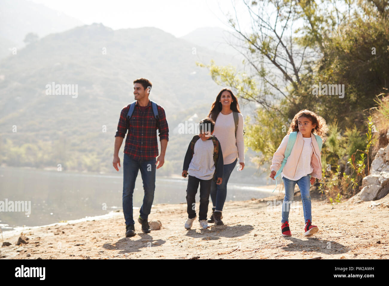 Eltern und Kinder wandern von einem Bergsee im Sonnenschein Stockfoto