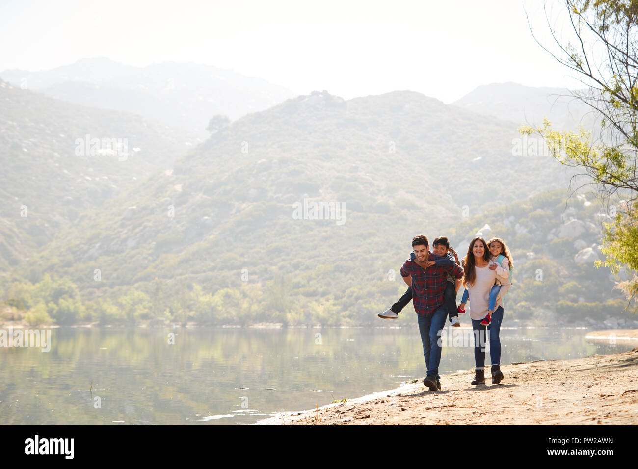 Huckepack Eltern ihre Kinder von einem Bergsee Stockfoto