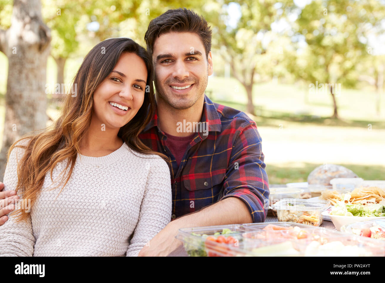 Junges Paar am Picknicktisch lächelnd in die Kamera Stockfoto