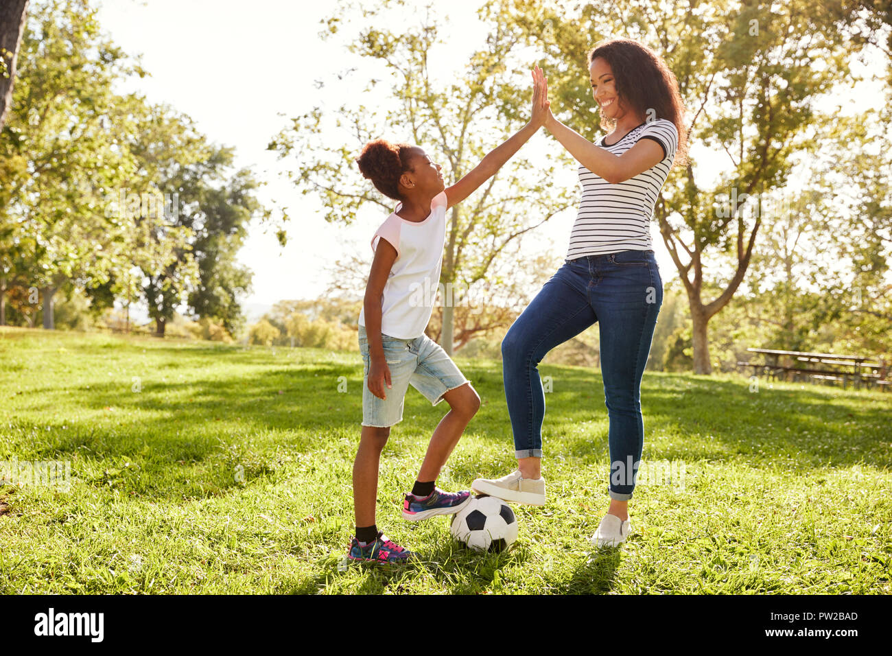 Mutter und Tochter Fußball spielen im Park zusammen Stockfoto