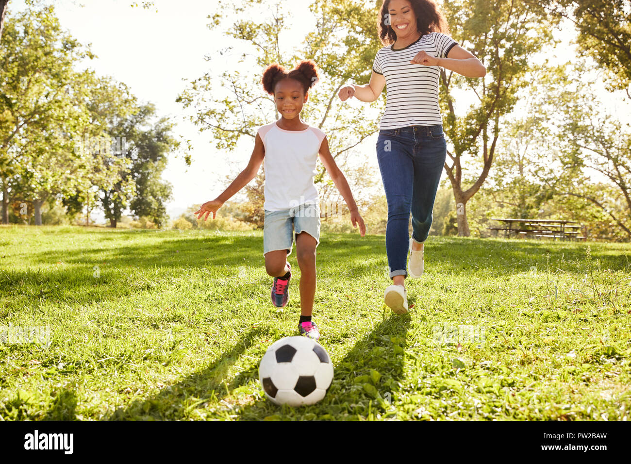 Mutter und Tochter Fußball spielen im Park zusammen Stockfoto
