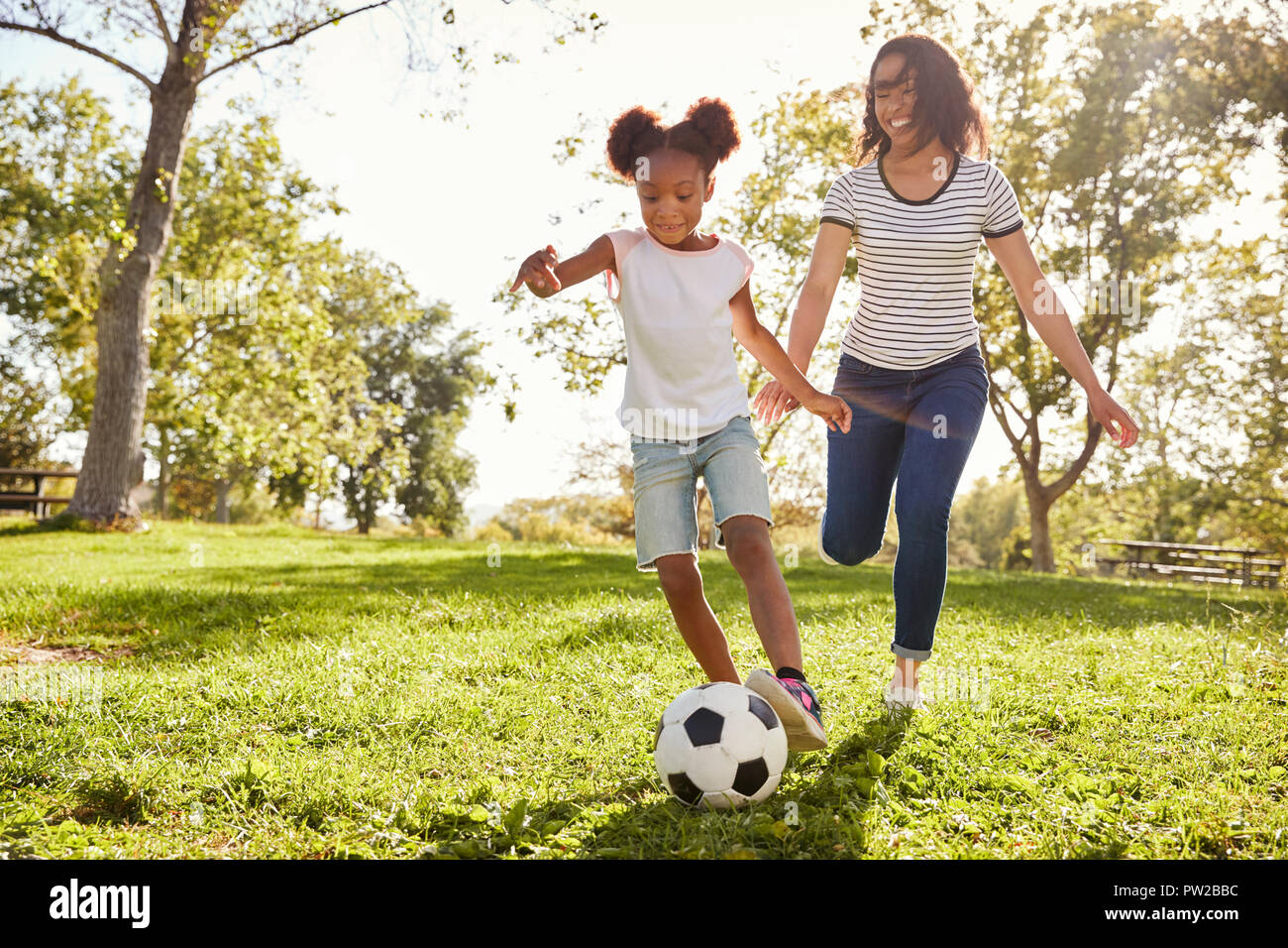 Mutter und Tochter Fußball spielen im Park zusammen Stockfoto