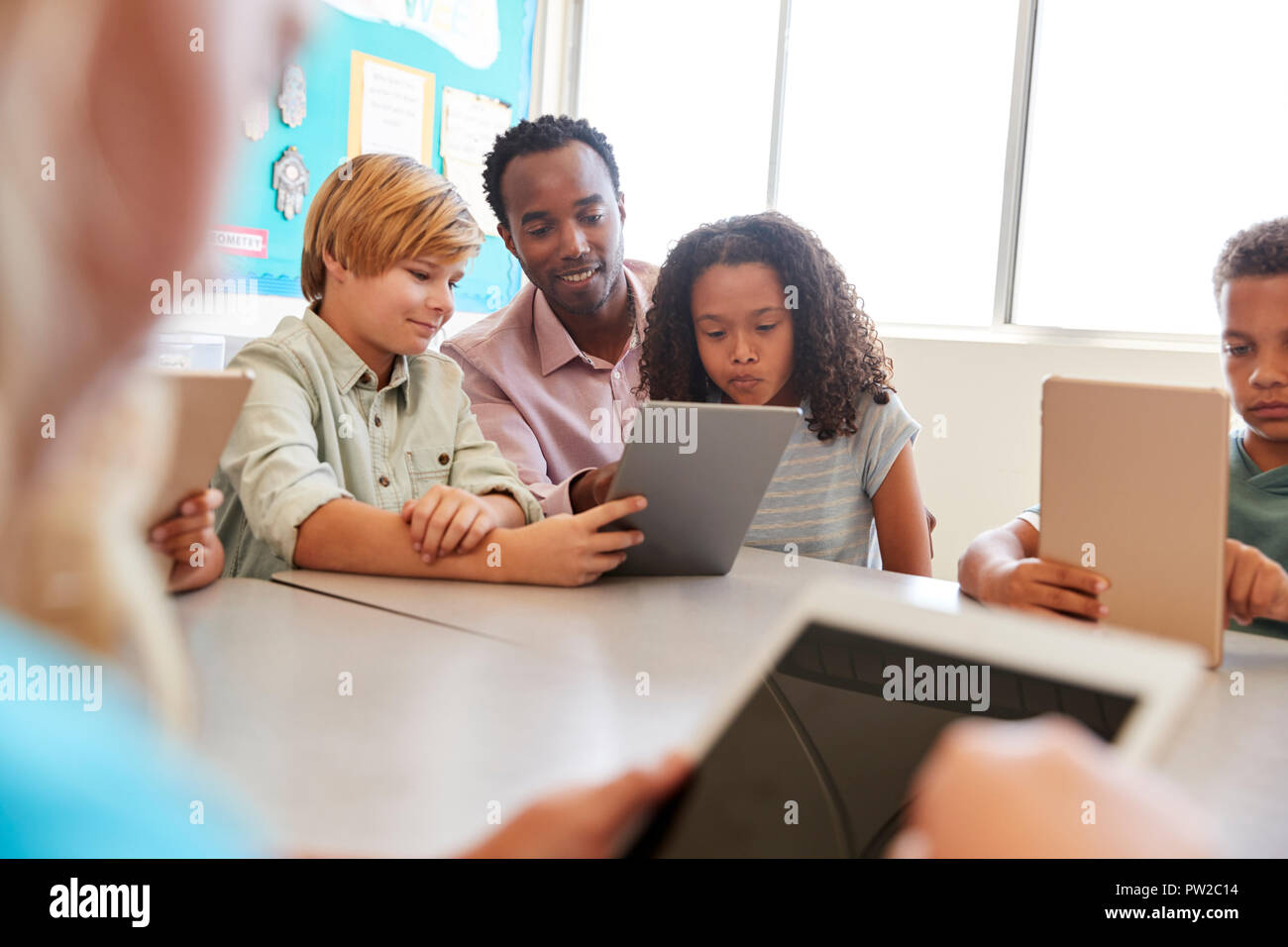 Lehrer sitzt mit kleinen Kindern die Verwendung von Computern in der Schule Klasse Stockfoto