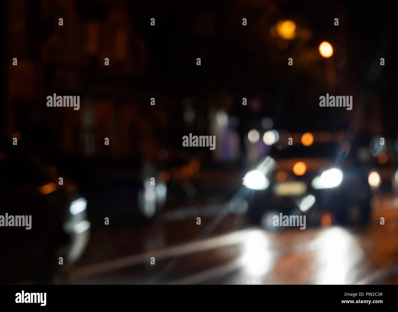 Verschwommen Auto leuchtet auf einer nassen Straße nach dem Regen Stockfoto