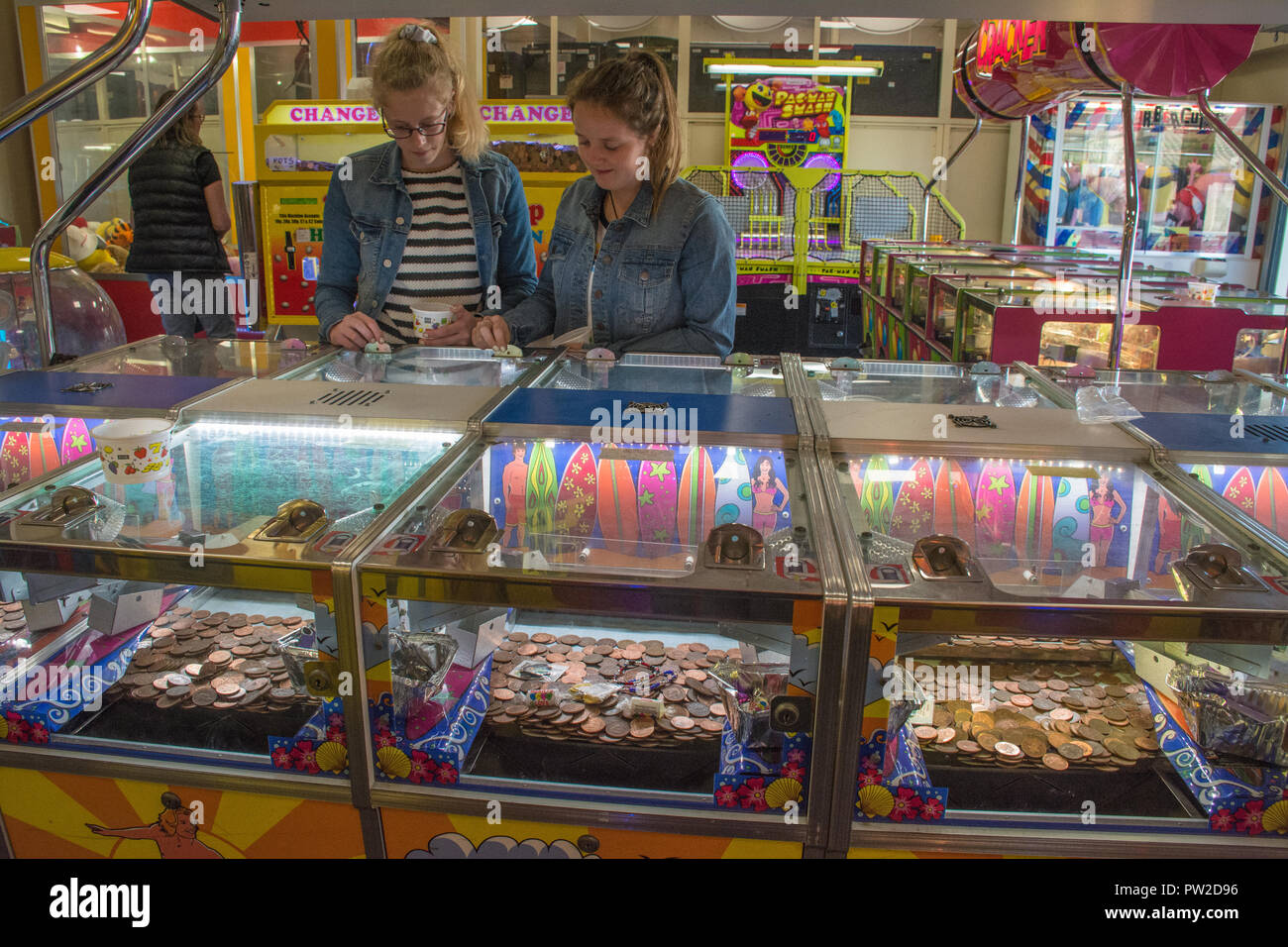 Zwei Mädchen im Teenager-Alter spielen auf dem Slot Maschinen in eine Spielhalle in Hayling Island, Hampshire, Großbritannien Stockfoto
