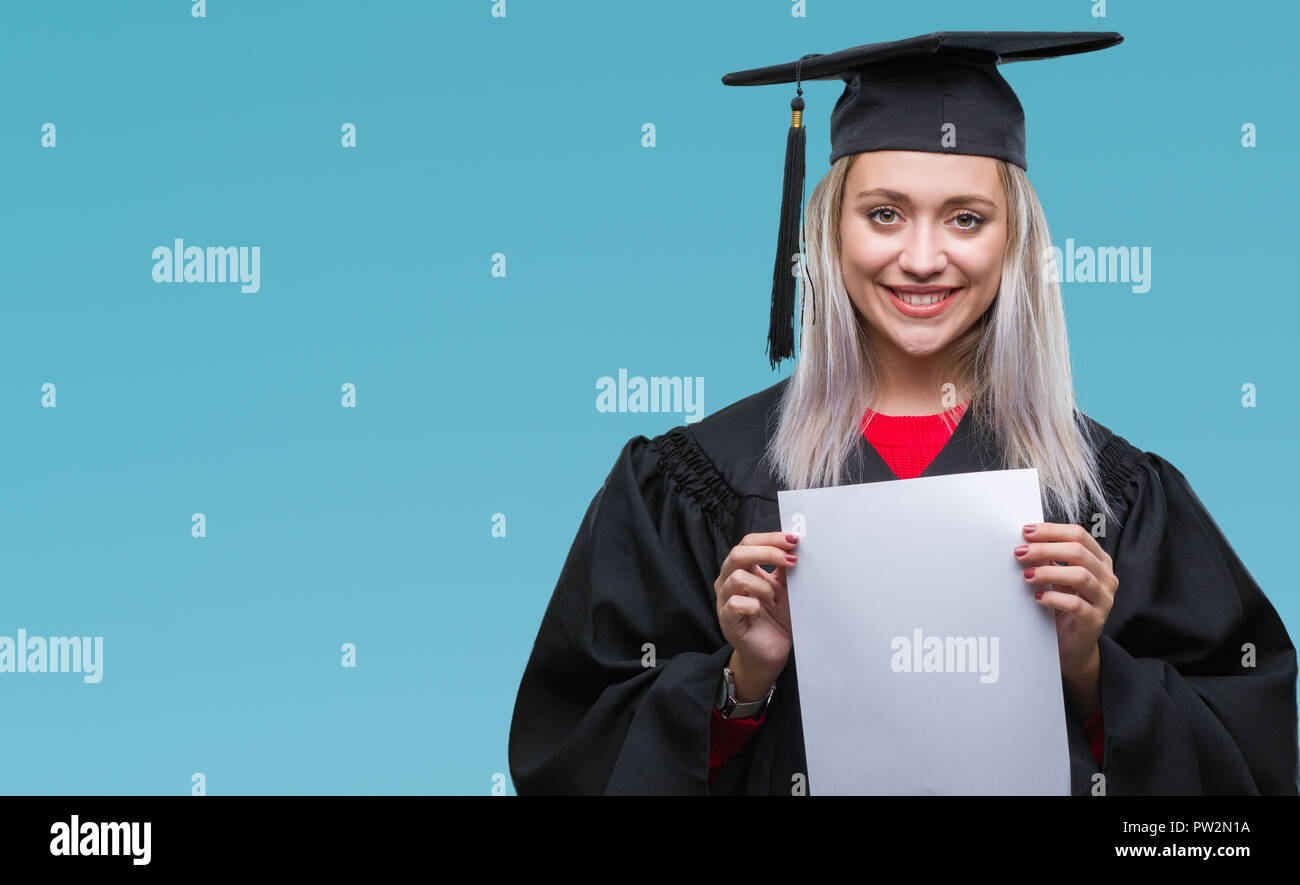 Junge blonde Frau tragen Absolvent einheitliche Holding Grad über isolierte Hintergrund mit einem glücklichen Gesicht stehen und lächelnd mit einem selbstbewussten Lächeln zeigen Stockfoto