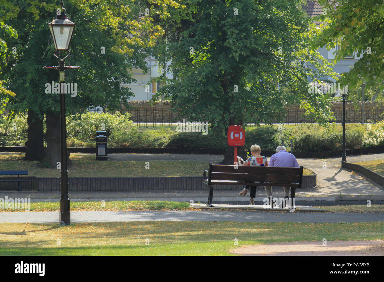 Ein Mann und eine Frau saß auf einer Bank durch den Fluss in Abbey Park Evesham Stockfoto