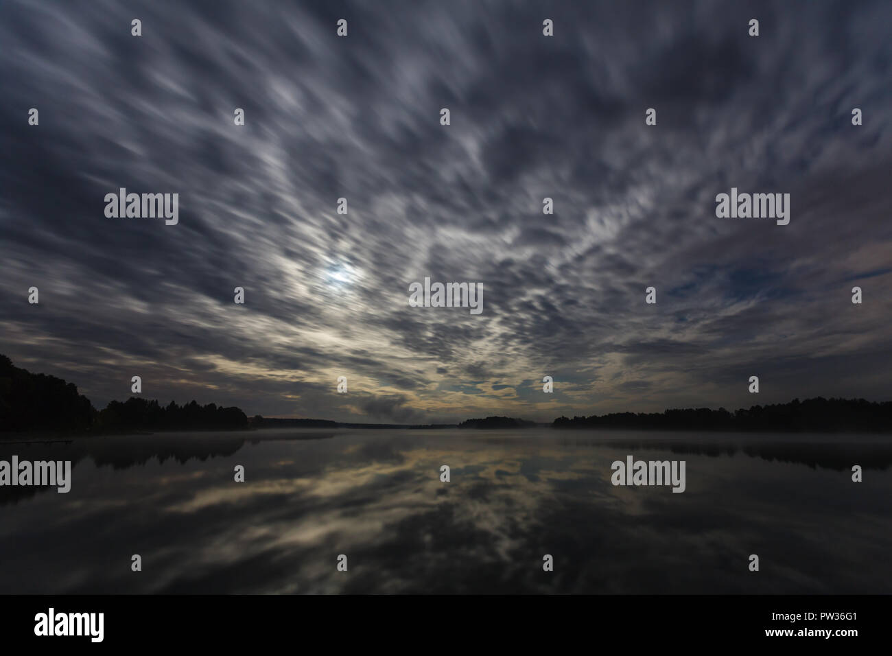 Dynamische Wolken in der Nacht über den See leuchtet bei Vollmond, Langzeitbelichtung Schuss Stockfoto