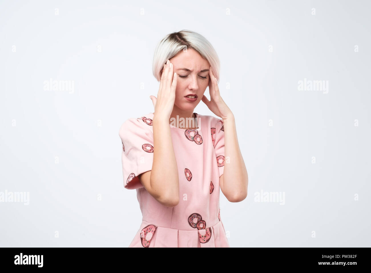 Porträt der schönen jungen Frau im rosa Kleid Sie zu berühren Tempel Stress Stockfoto