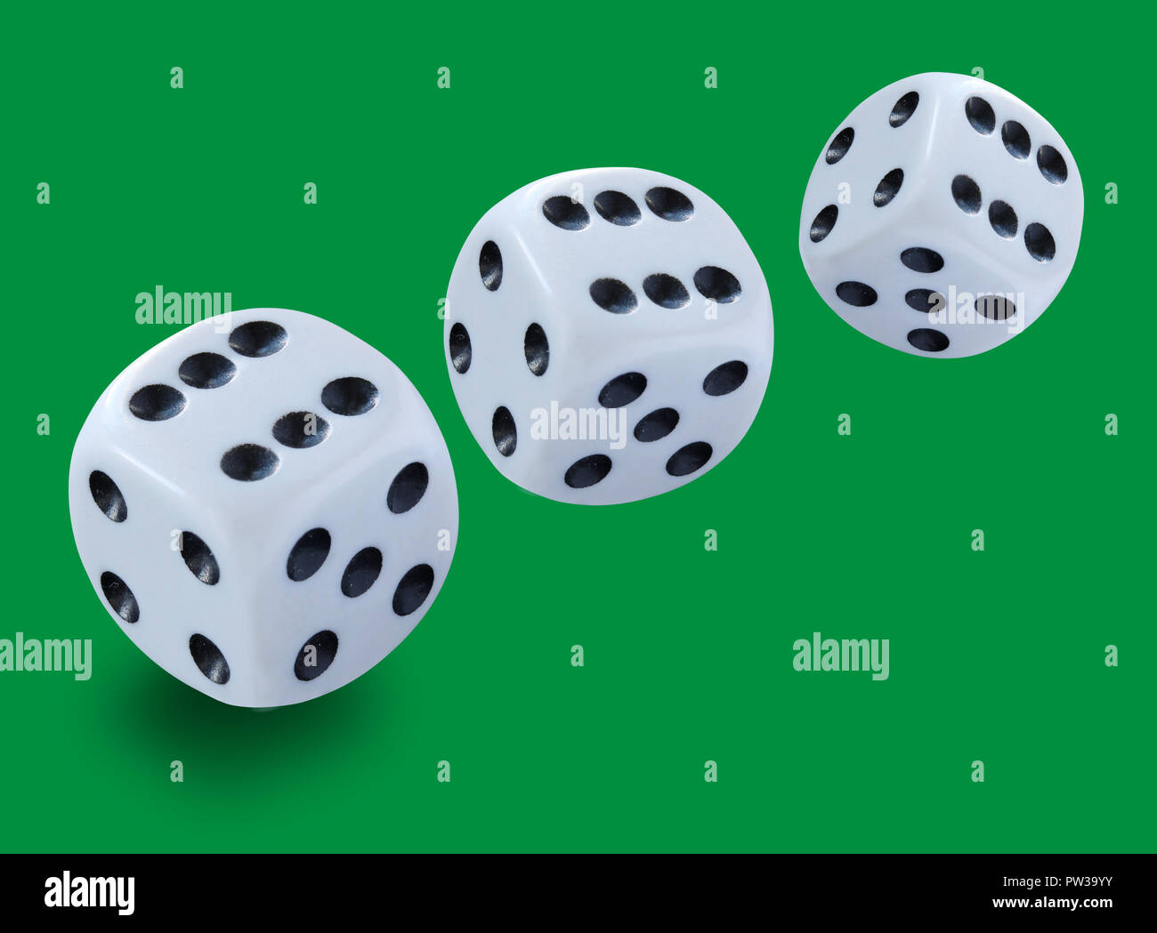 Drei weisse Würfel unterschiedlicher Größe in einem Craps Spiel Yahtzee oder jede Art von würfelspiel vor einem grünen Hintergrund geworfen Stockfoto