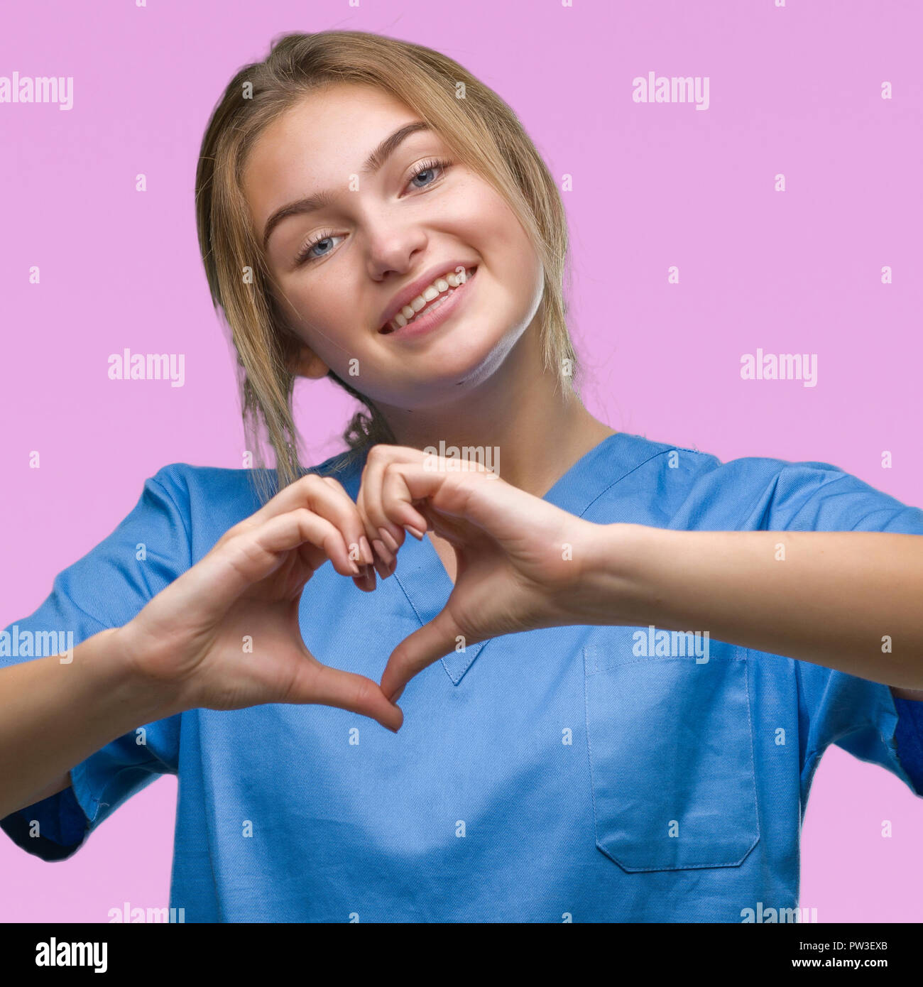 Junge kaukasier Krankenschwester Frau tragen Chirurgen gleichmäßig über isolierte Hintergrund lächelnd in Liebe mit Herz und Formen mit den Händen. Romantische conce Stockfoto