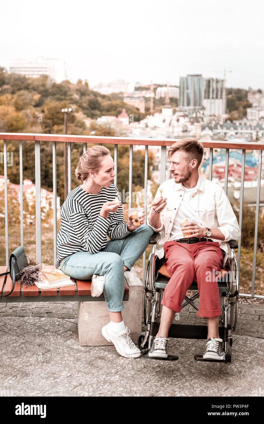 Behinderte Menschen die Stirn runzelte und das Essen von Früchten mit seinem Freund Stockfoto