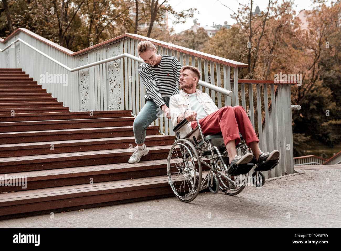 Ungültige Mann mit Blick auf die junge Frau, die seinem Rollstuhl Stockfoto