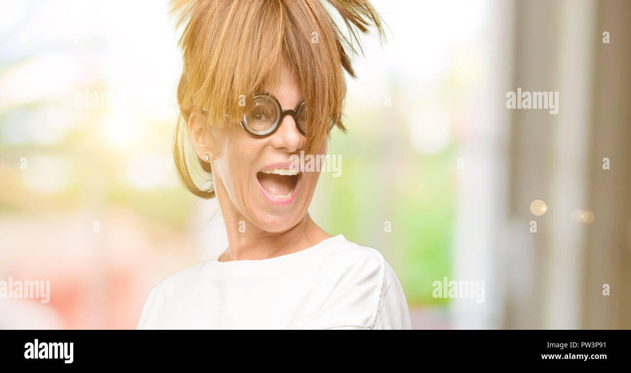 Crazy mittleren Alter Frau mit dummen Gläser etwas Holding in leere Hand Stockfoto