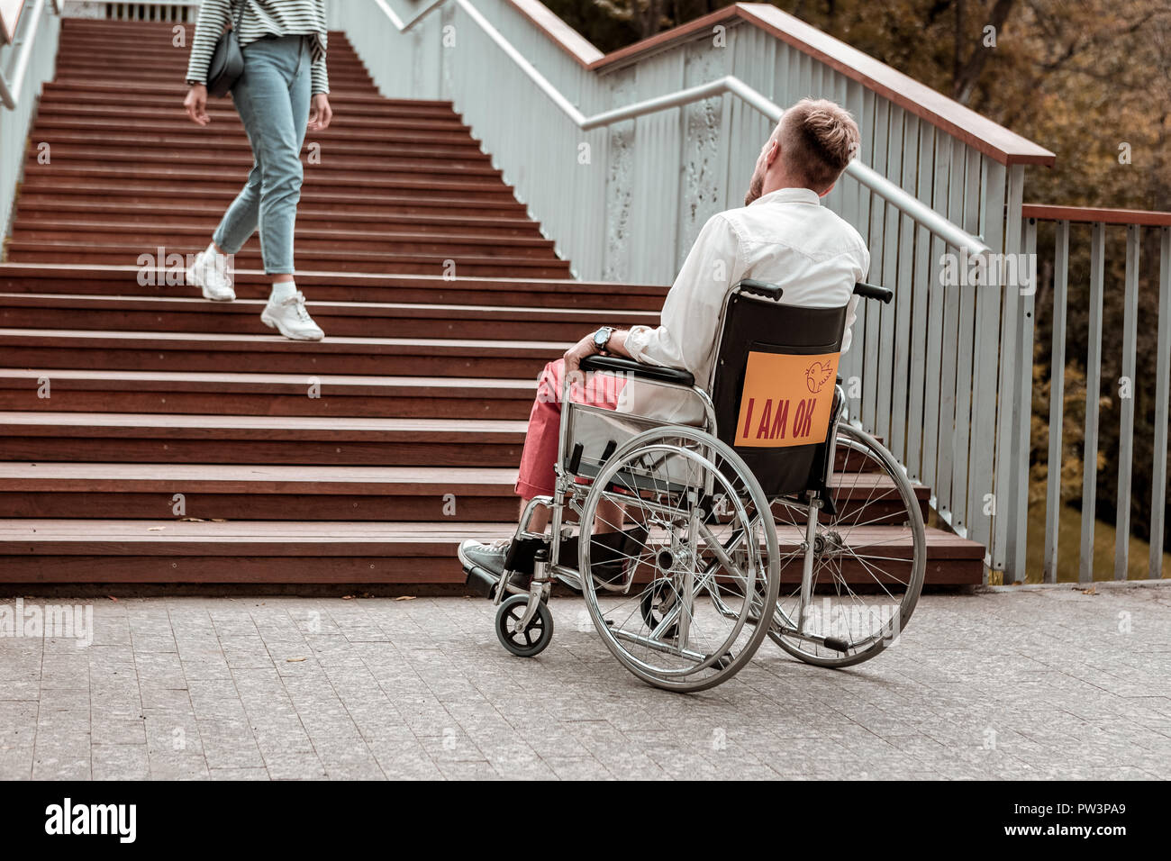 Ungültige Mann sitzt im Rollstuhl und mit Blick auf die Treppe Stockfoto