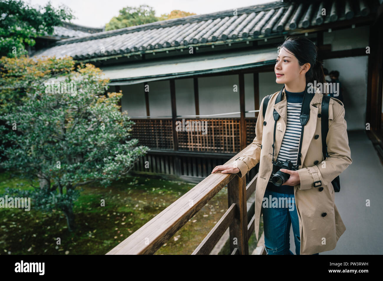 Attraktive Frau, die Hände auf das Geländer und entspannende Sehen der Blick auf den Garten. touristische Lebensstil in Japan. Traveler friedlich zu Fuß in Stockfoto