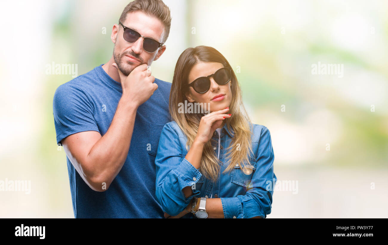 Junges Paar in der Liebe tragen Sonnenbrillen über isolierte Hintergrund mit der Hand am Kinn über die Frage denken, nachdenklichen Ausdruck. Lächelnd mit thoughtfu Stockfoto