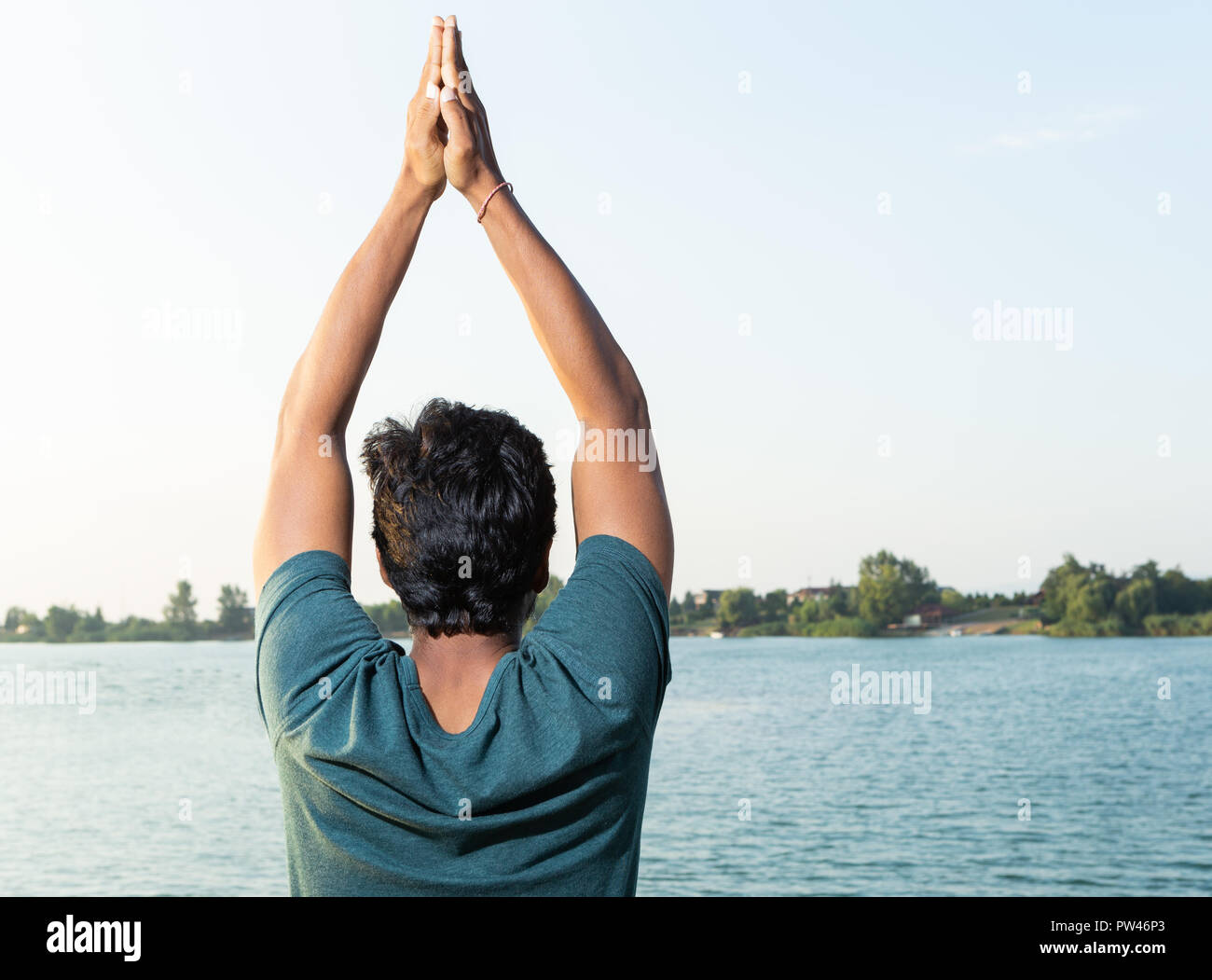 Indische yoga Master mit hands up pose Bild von hinten in der Nähe von natürlichen Hintergrund mit See Stockfoto