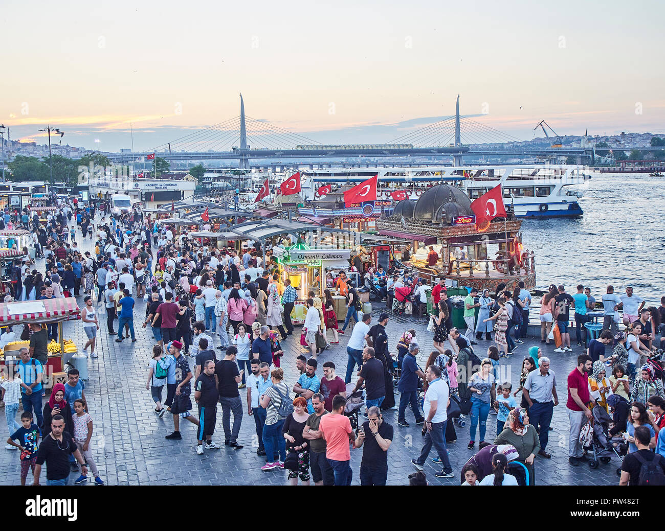 Istanbul, Türkei - 7. Juli 2018. Touristen, die in der Eminonu Pier bei Sonnenuntergang, mit Blick auf das Goldene Horn Bucht mit dem Fisch sandwich Boote und die halic B Stockfoto