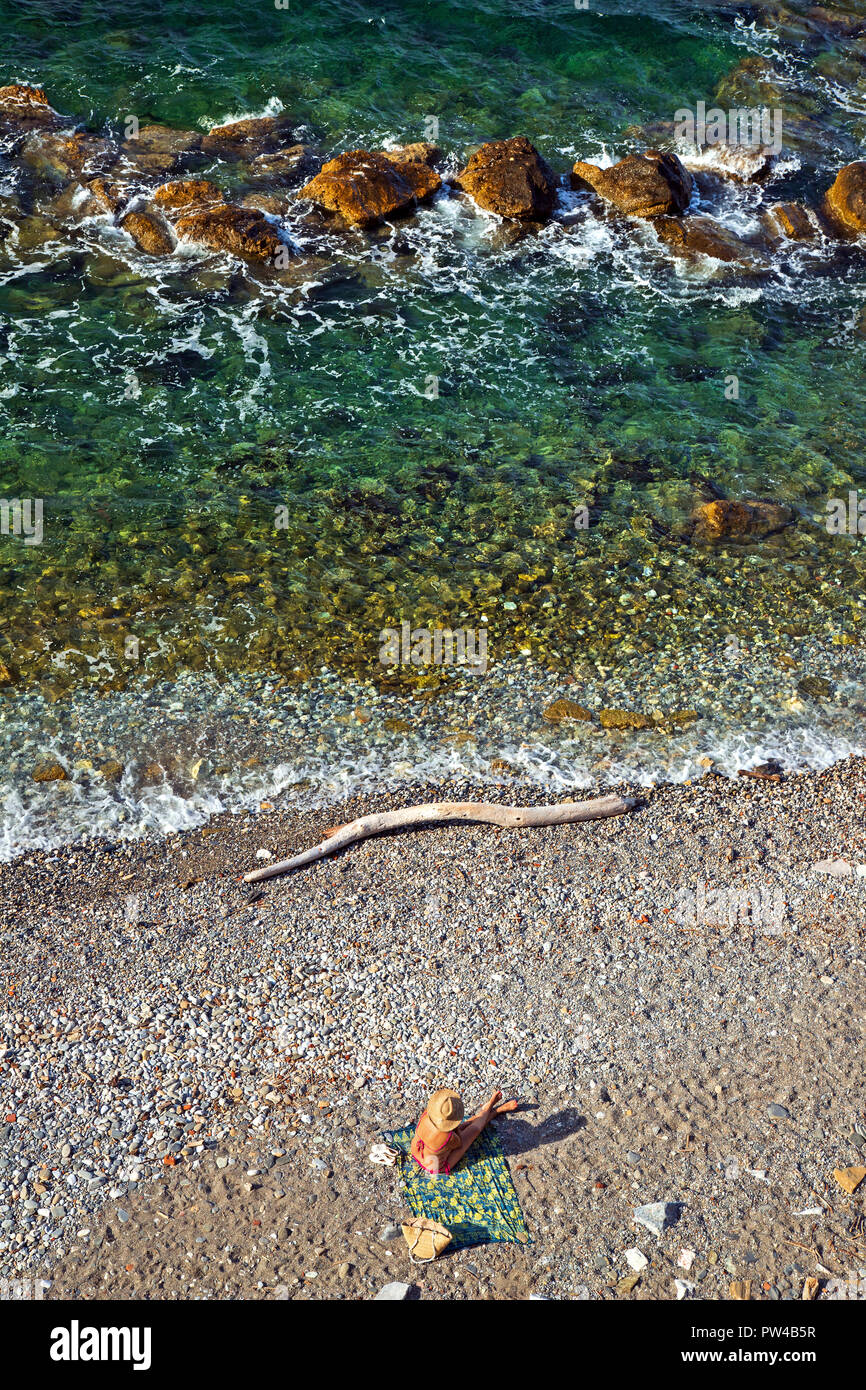 Einsame Frau am Strand rechts unter Kastro ('Castle') Nachbarschaft, Skopelos Stadt, Insel Skopelos, Nördliche Sporaden, Griechenland. Stockfoto