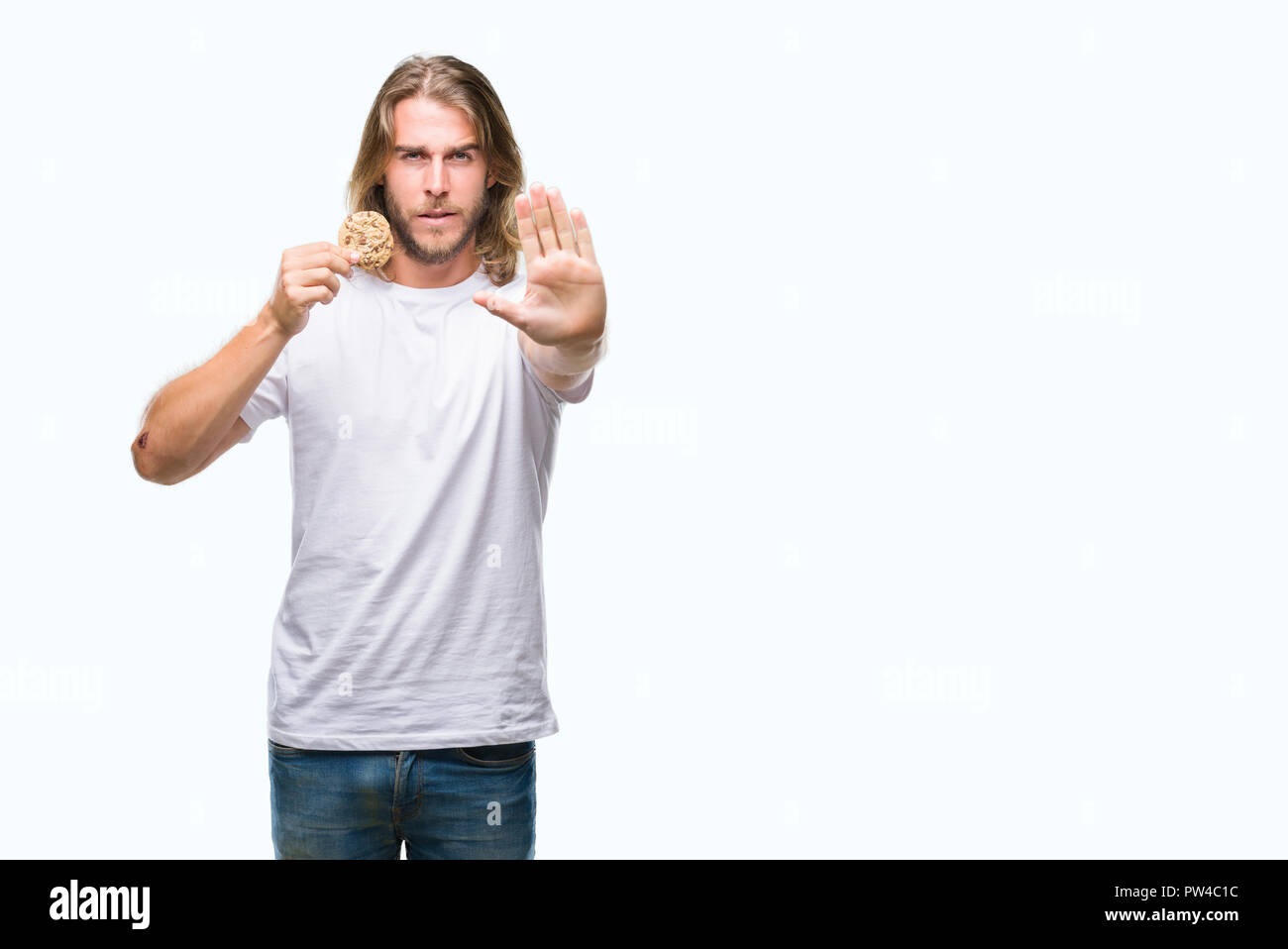 Junger stattlicher Mann mit langen Haaren Schokolade essen Cooky über isolierte Hintergrund mit der offenen Hand tun, STOP-Schild mit ernsten und selbstbewussten Ausdruck Stockfoto