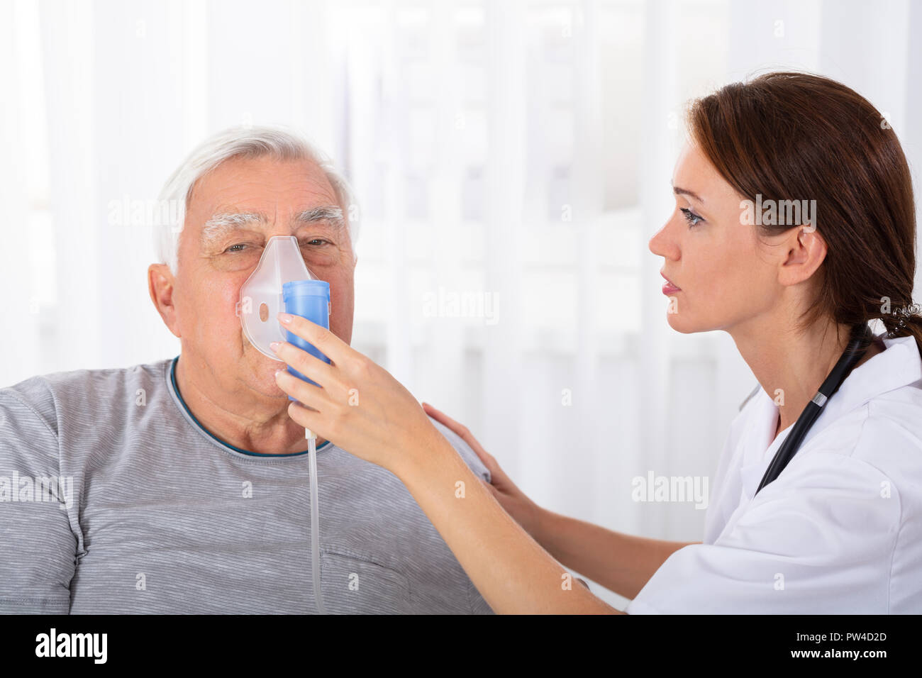 Junge Ärztin Holding Sauerstoff Maske über von männlichen Patienten Gesicht Stockfoto