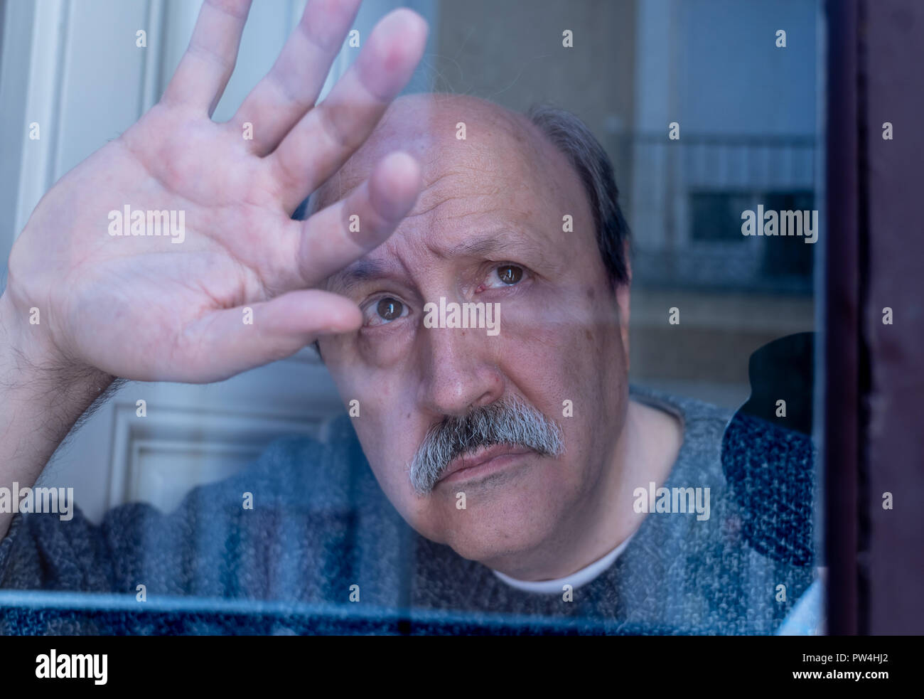 Alte älterer Mann, während das Fenster Verwirrung und allein zu Hause in alternden Ruhestand Witwer Demenz und Alzheimer Konzept deprimiert. Stockfoto