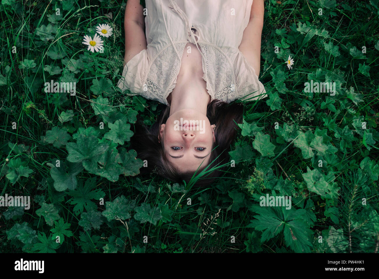 Hohen winkel Portrait von unbeschwerte junge Frau liegt inmitten Pflanzen auf dem Feld im Wald Stockfoto